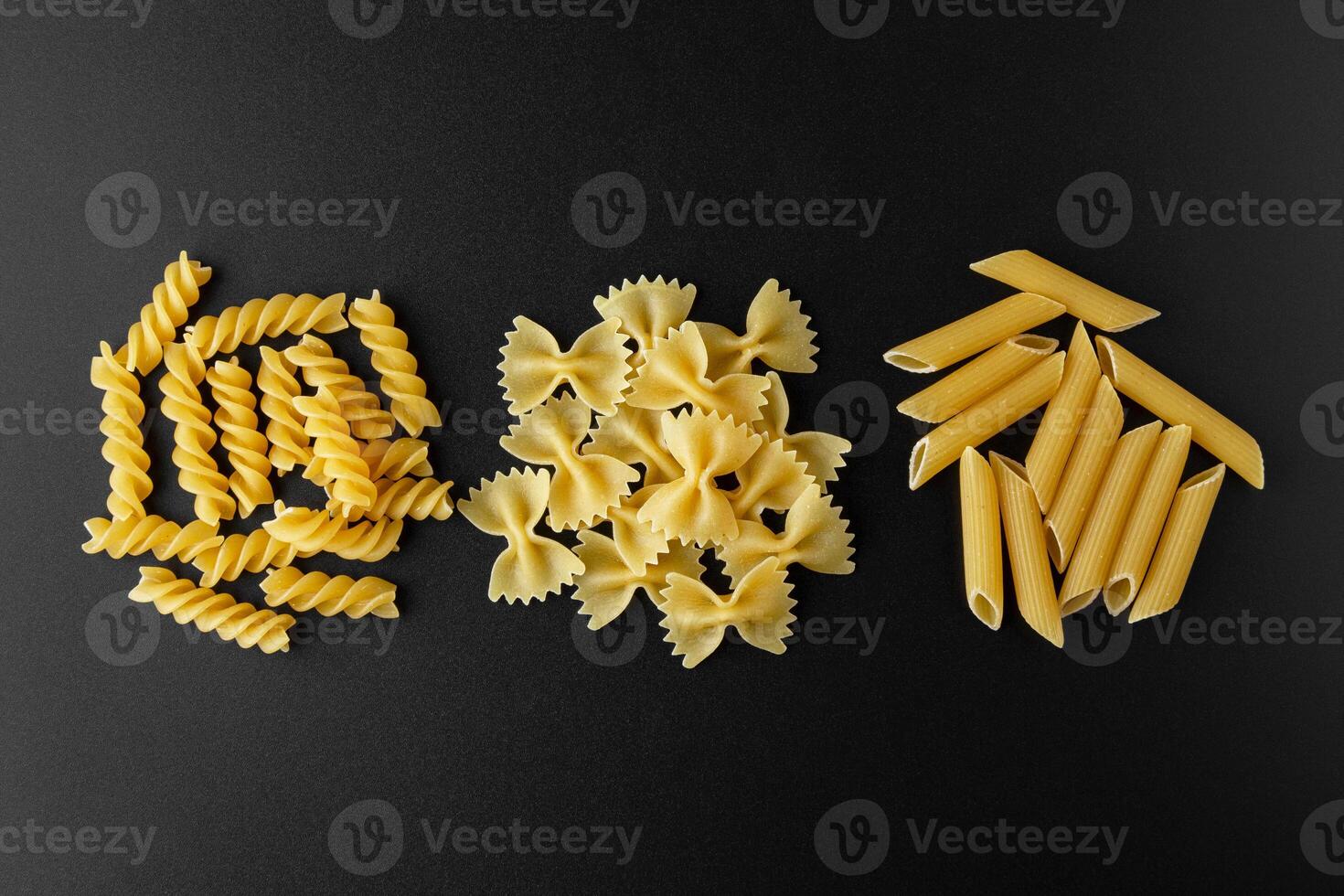 Different kinds of raw pasta with copy space on black background. photo