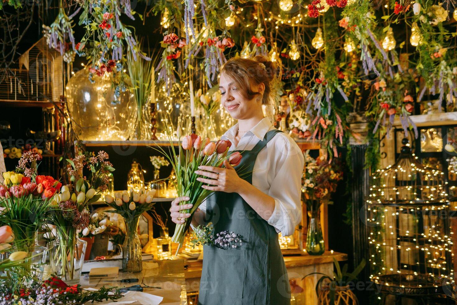 A woman in her florist shop collects bouquets of flowers. The concept of a small business. Bouquets of tulips for the holiday on March 8. photo