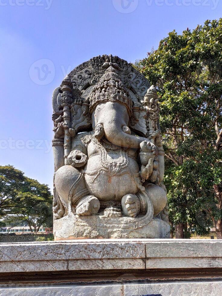Lord Ganesha sculpture at Halebidu Temple, Karnataka. Depicted seated in a meditative pose with traditional symbols like an axe and sweets, with detailed jewelry, and garments showcasing craftsmanship photo