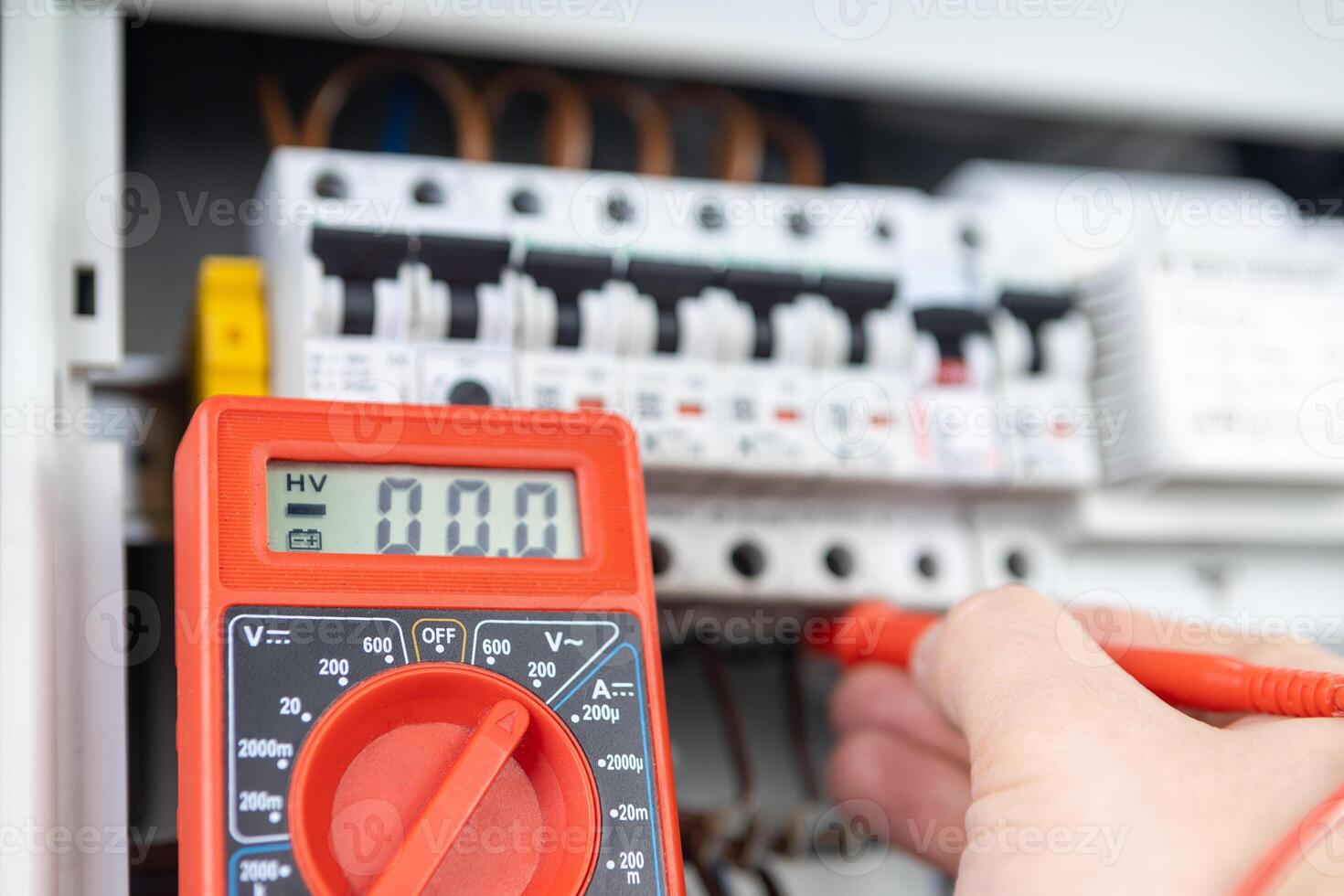 Electrician Measuring Voltage with Multimeter in Circuit Breaker Panel photo