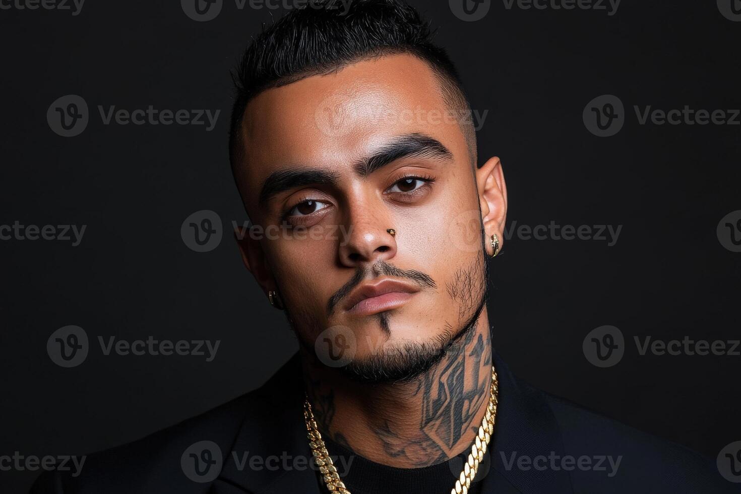 A confident man poses with a serious expression against a dark background photo