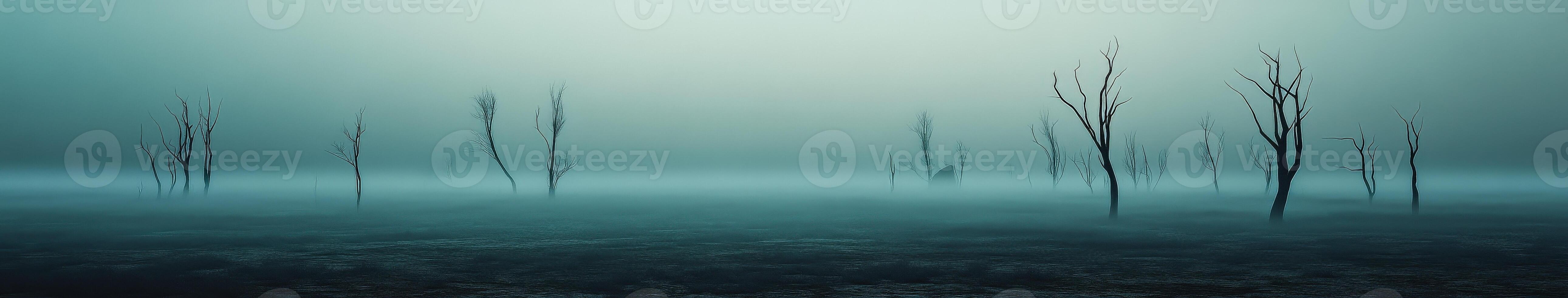 Fog envelops barren trees in a desolate landscape at dawn photo