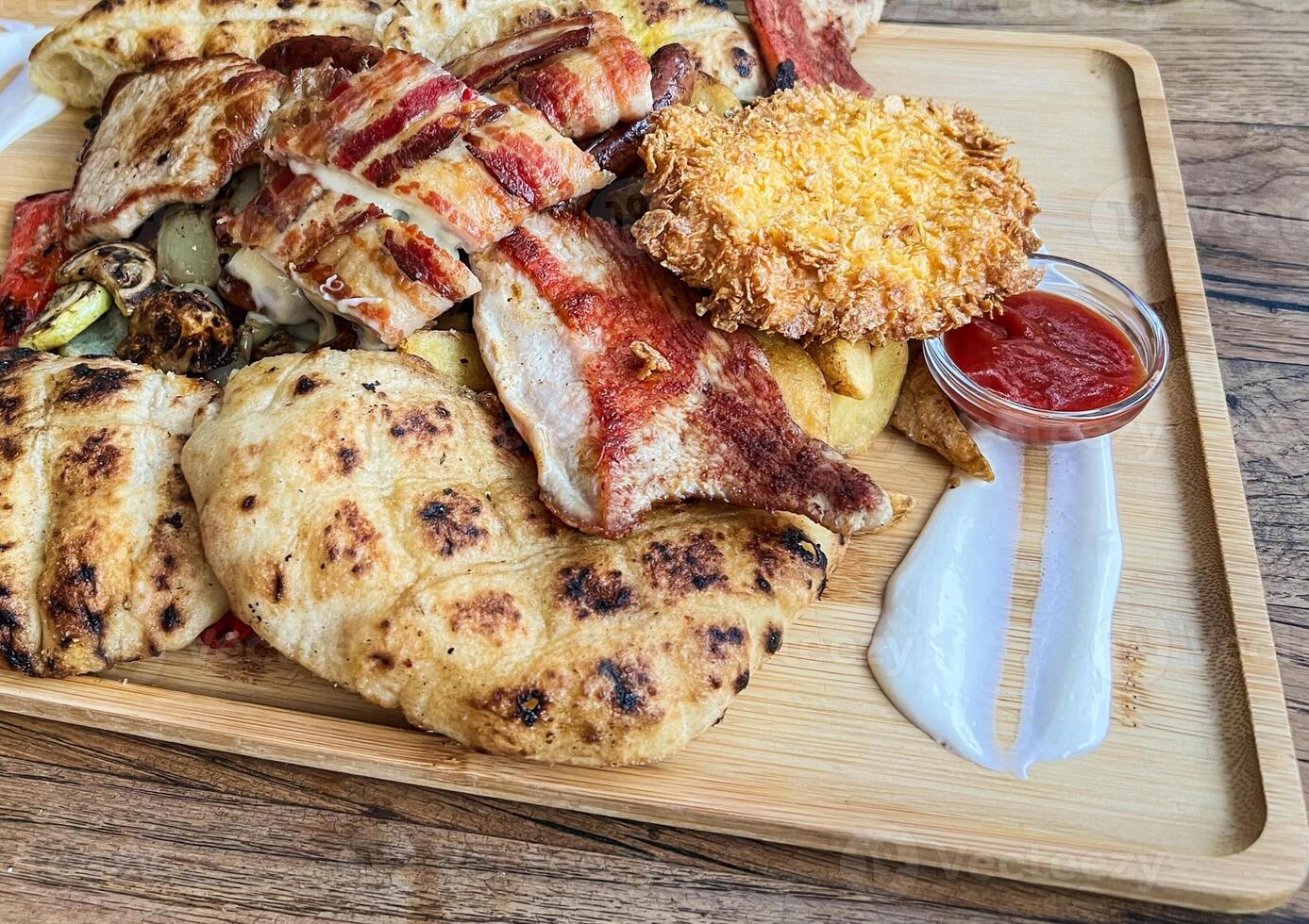 Grilled pork chops and meat bacon steaks and grill with ketchup on wooden board photo