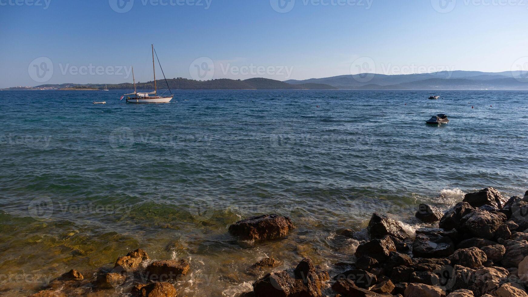 Adriatic Sea with a boat on the left and rocky shoreline on the right photo