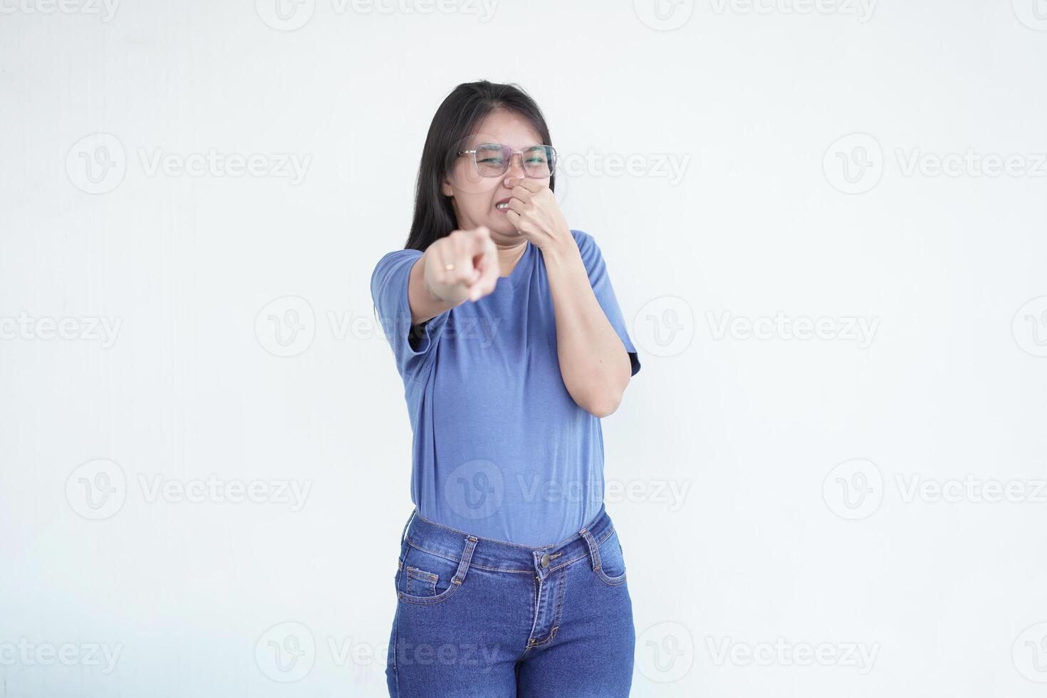 beautiful Asian woman shows a wrinkled nose in reaction to a smell while covering her nose against a white background photo
