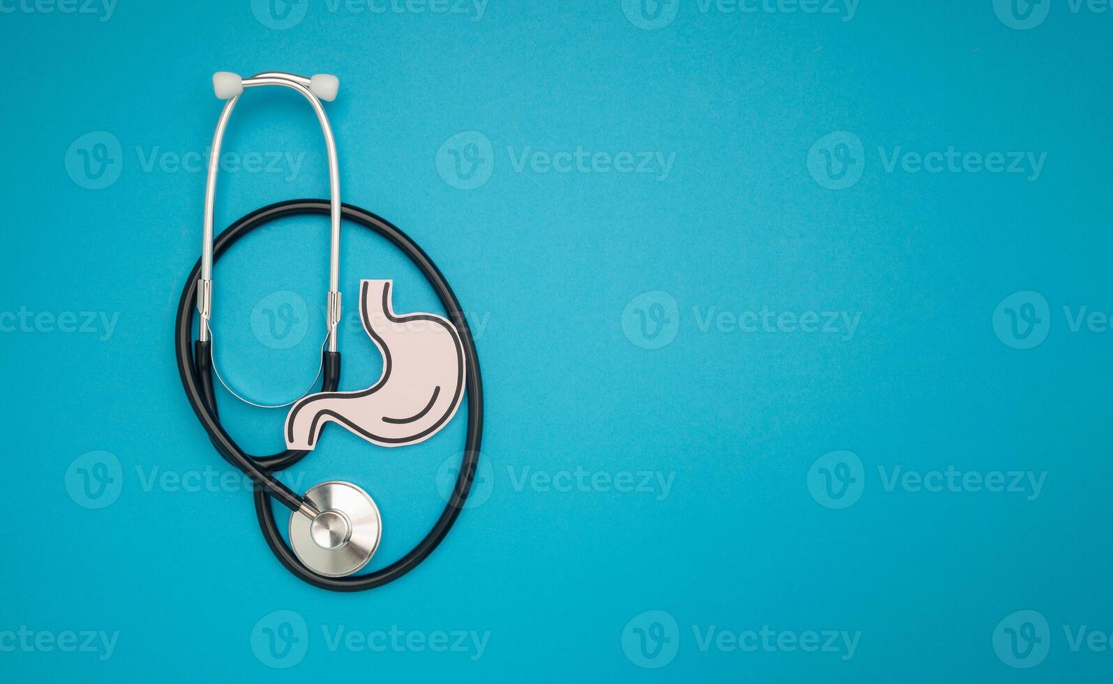 A stethoscope and stomach shape made from paper are over a blue background photo