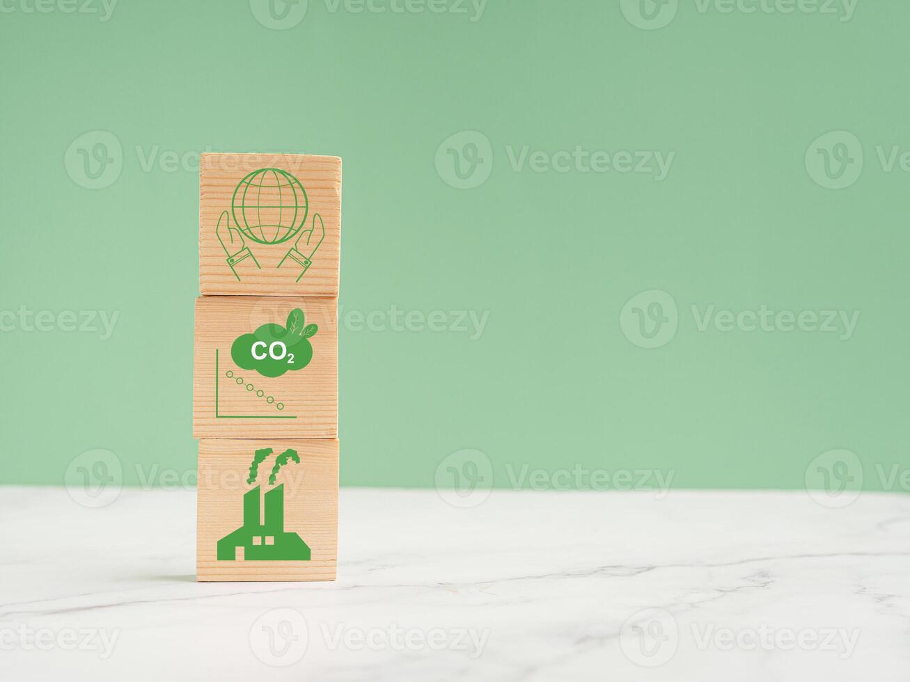 Net-zero greenhouse gas emissions target. Wooden cubes with green icons over a marble floor against a light green background photo