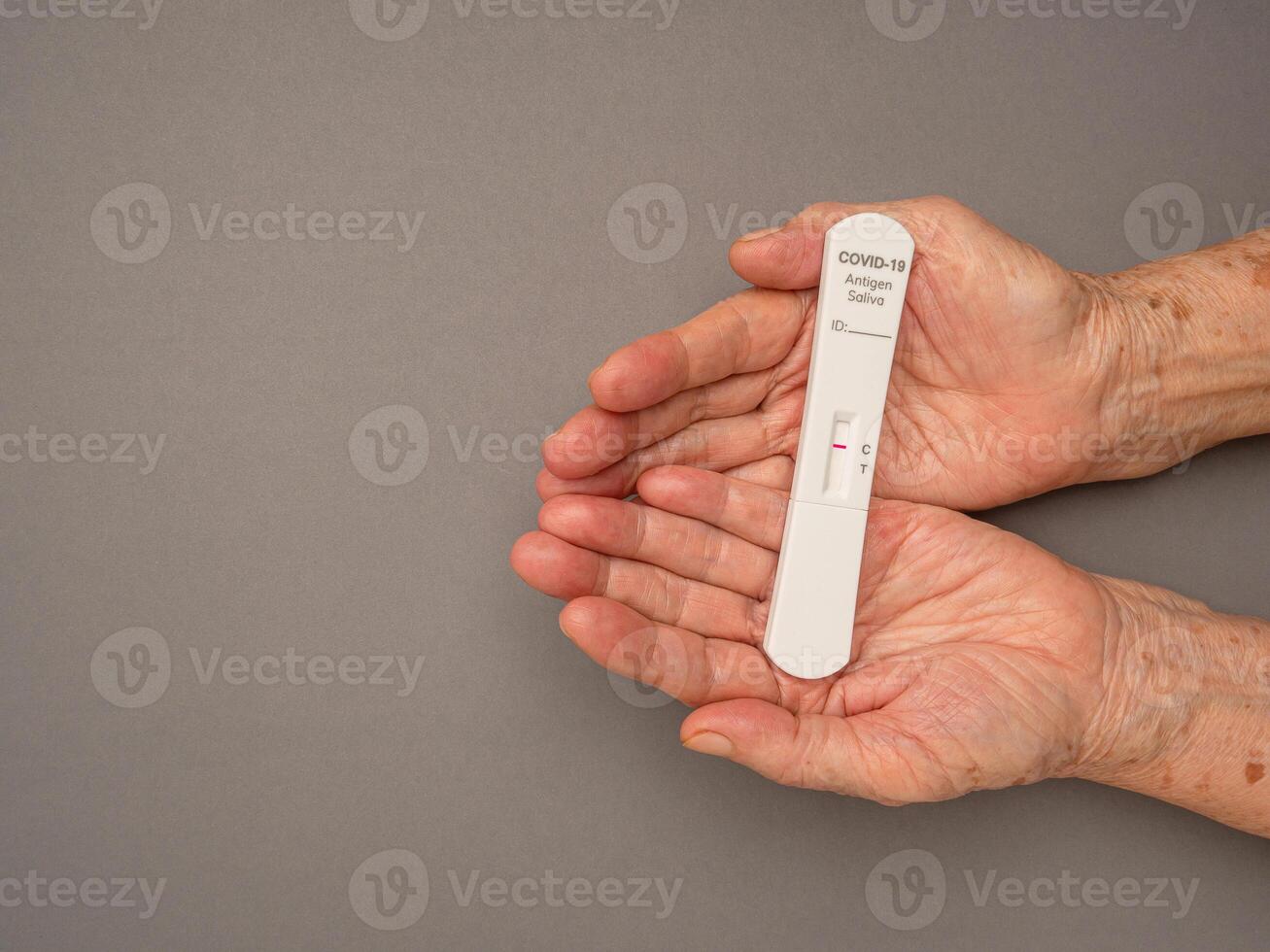 Senior woman hands holding Covid-19 Negative test result with SARS-COV-2 Saliva Antigen Rapid Test Kit photo