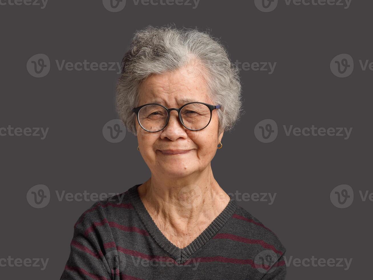 Portrait of a senior woman with short gray hair looking at the camera with a smile while standing on gray background photo