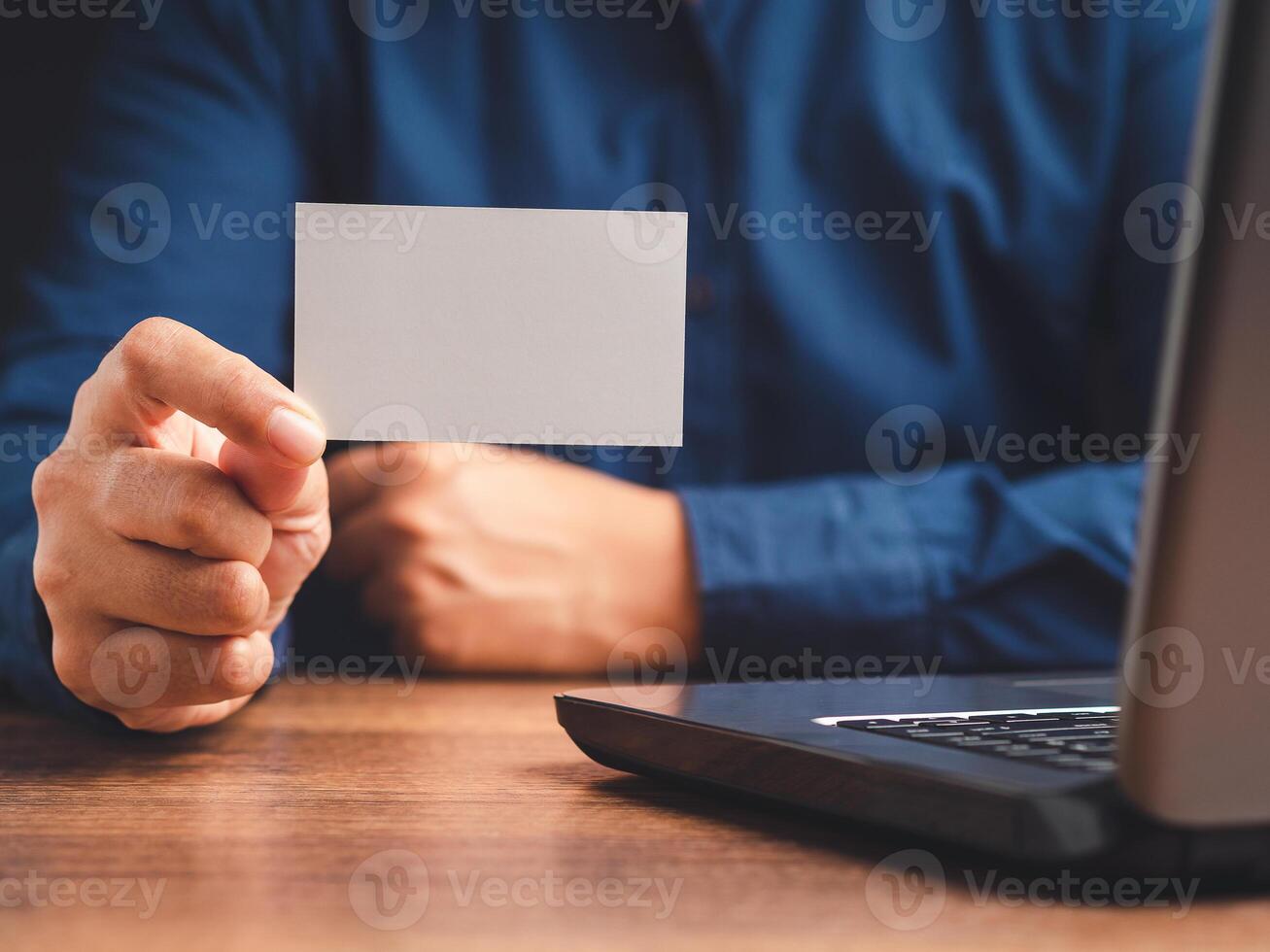 Close-up of hand holding a blank white paper while sitting in the office photo