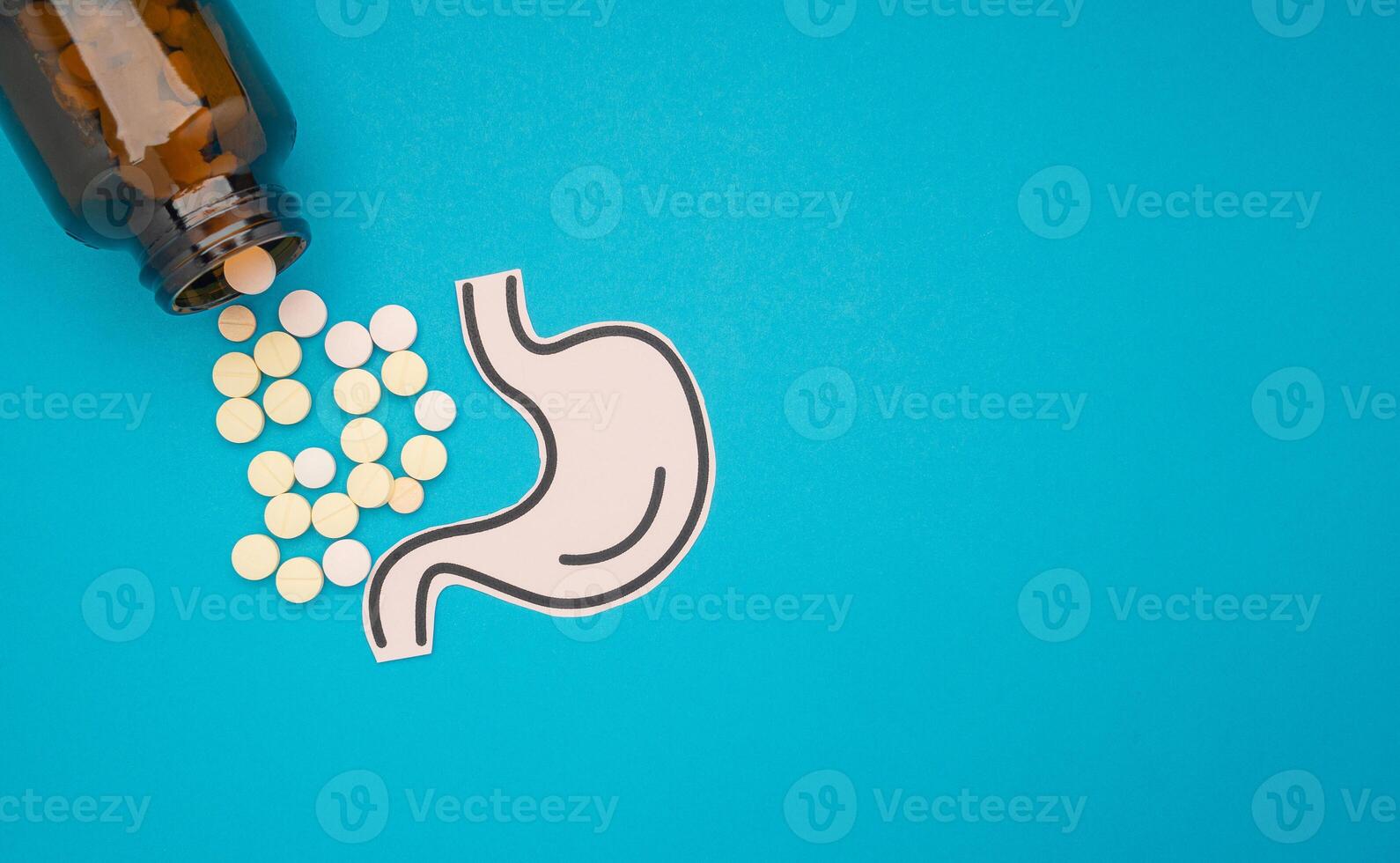 Stomach shape made from paper and pills with a bottle on a blue background photo