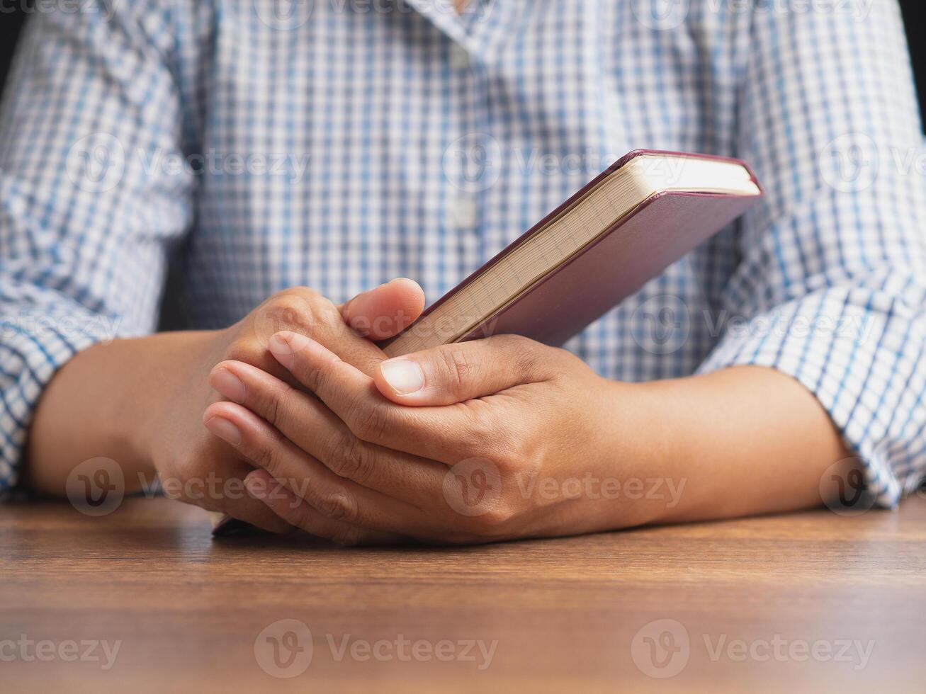 Close-up of hand holding a book with a red cover while sitting in the library photo