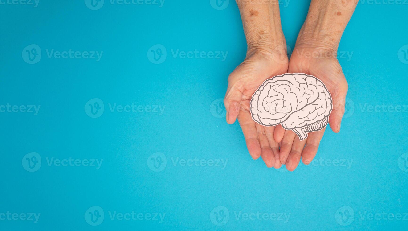 Brain shape made from paper on a palm senior woman on a blue background photo