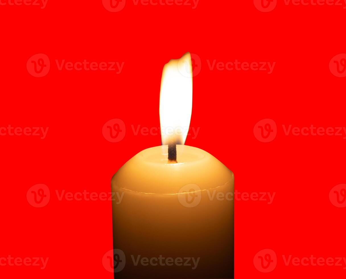 A single burning candle flame or light glowing on a big white candle isolated on red background with clipping path photo