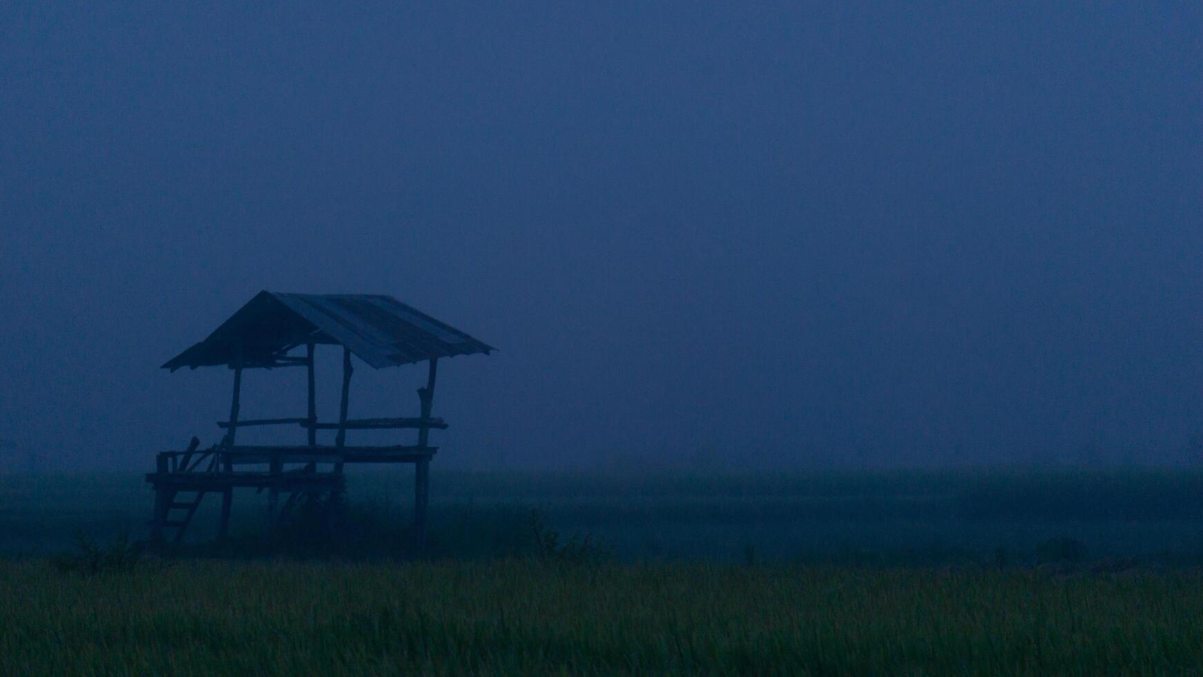 Silhouetted Wooden Hut in Foggy Twilight Landscape photo