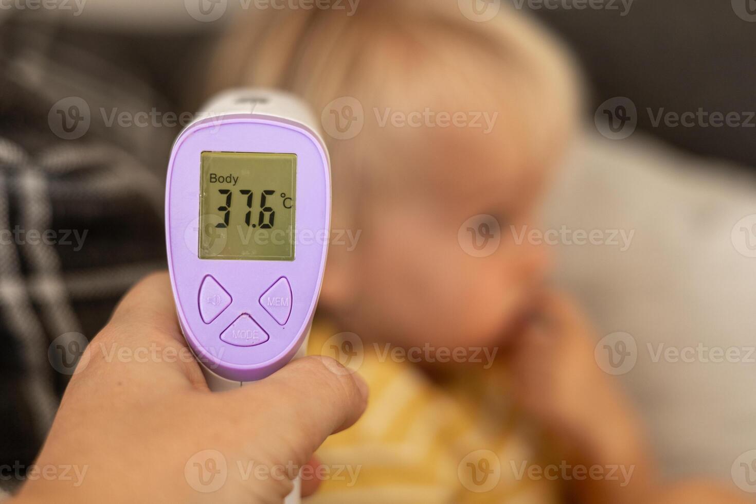 Parent checks childs body temperature with digital thermometer at home during a wellness check photo