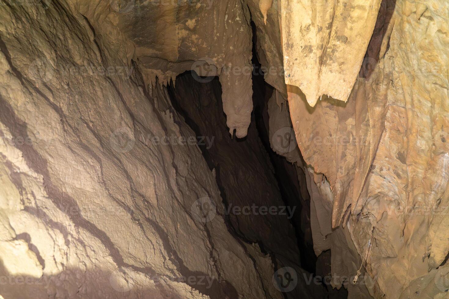 The cave is dark and has a lot of rock formations. The walls are covered in dirt and the ceiling is made of rock. photo