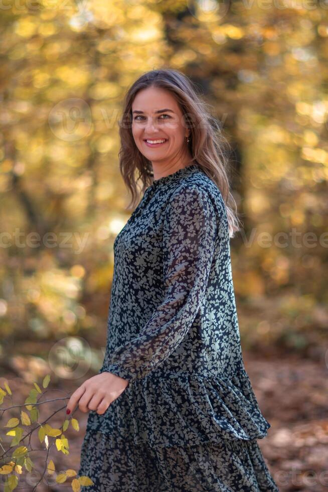 Woman Forest Fall Smiling Portrait - A woman smiles while standing in a forest during fall. photo