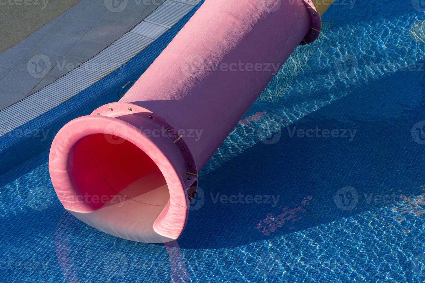 Water Slide Pool Summer Fun - Pink water slide ending in a pool of blue water on a sunny day, ready for a refreshing summer experience. photo