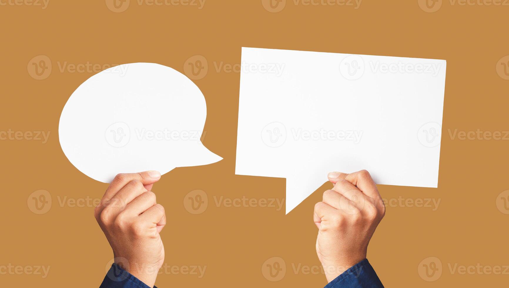Close-up of hands holding white speech bubbles against a light brown background photo