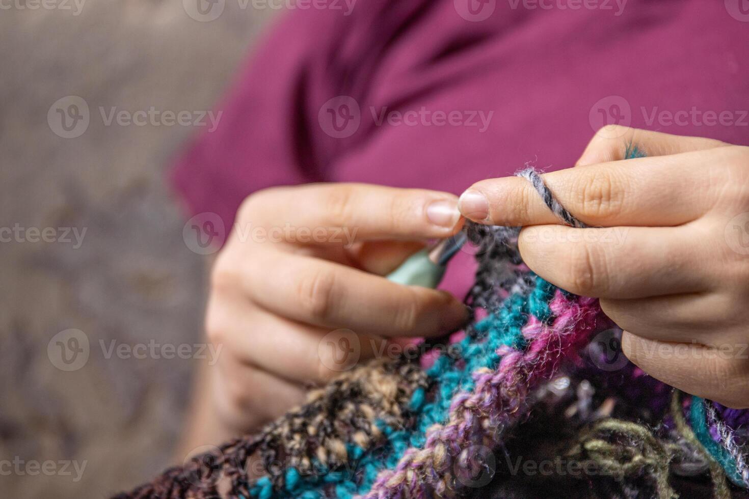 Young womans hands crochet colorful yarn with crocheting hook. Closeup details of handmade needlework art project and creative crafting techniques. Handmade textile artist knitting with yarn. photo