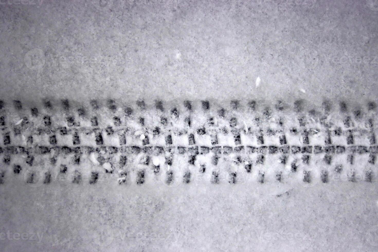 Detailed bicycle tire tread mark on fresh snow. Bike track pattern, texture left in a winter environment. Monochrome tire print on snow, providing a contrast of black against white. Copy space photo