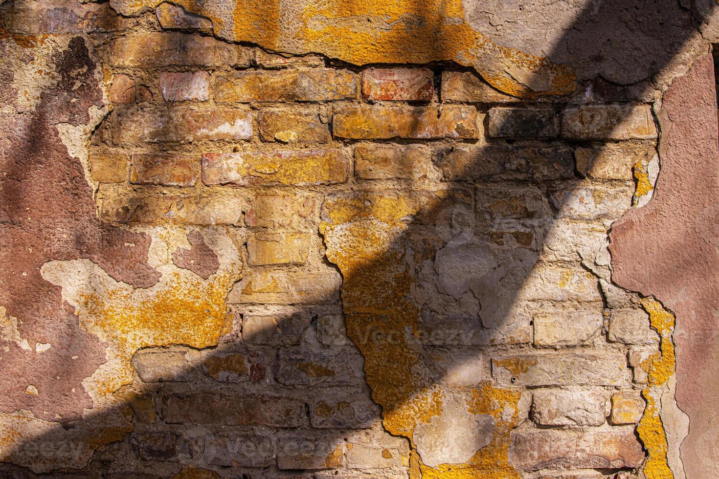 Closeup of a weathered bricks stone wall cracks and patina. Rough rustic texture and details of the aged surface, perfect for use in background and design projects. Urban decay aesthetic photo