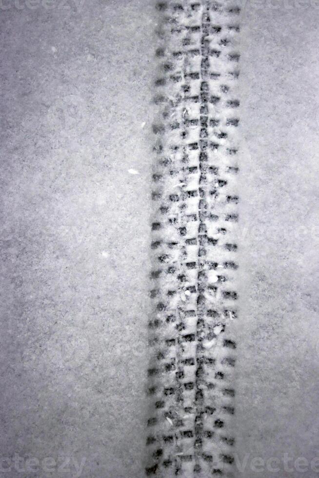 Detailed bicycle tire tread mark on fresh snow. Bike track pattern, texture left in a winter environment. Monochrome tire print on snow, providing a contrast of black against white. Copy space photo