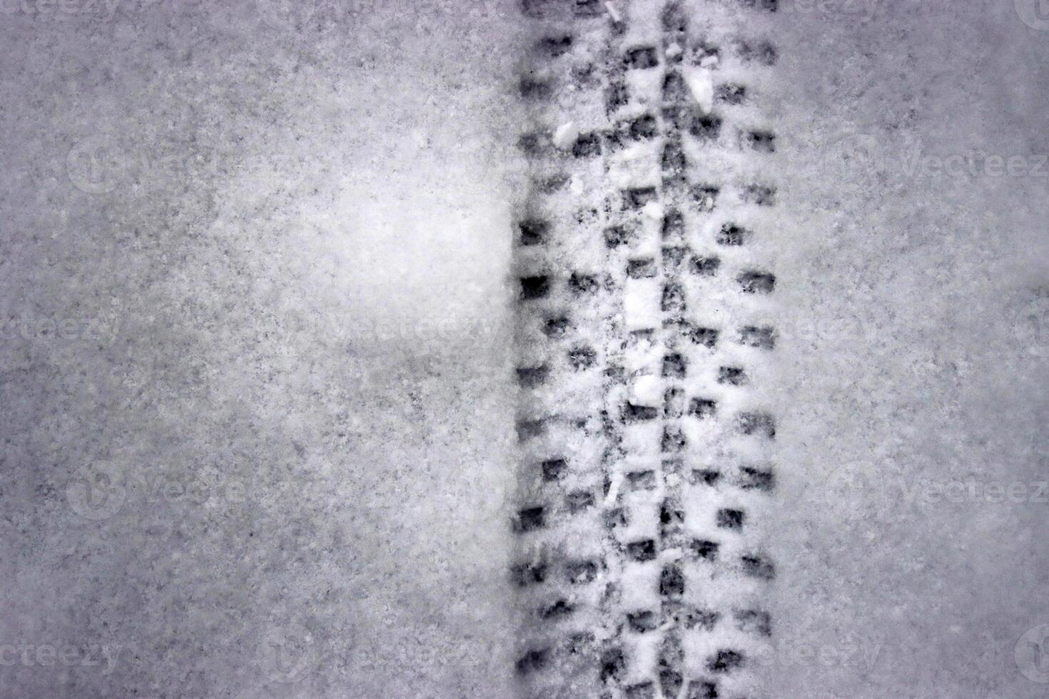 Detailed bicycle tire tread mark on fresh snow. Bike track pattern, texture left in a winter environment. Monochrome tire print on snow, providing a contrast of black against white. Copy space photo