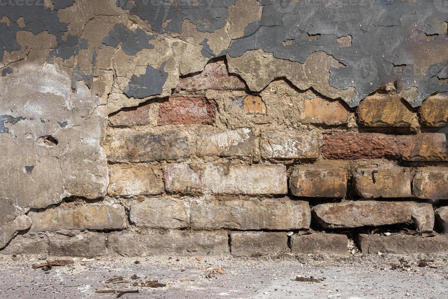 Old damaged broken shabby red brick wall of an old building. Brick texture with scratches and cracks. Grunge background with cracked grey blueish stucco. Close up. Copy space photo