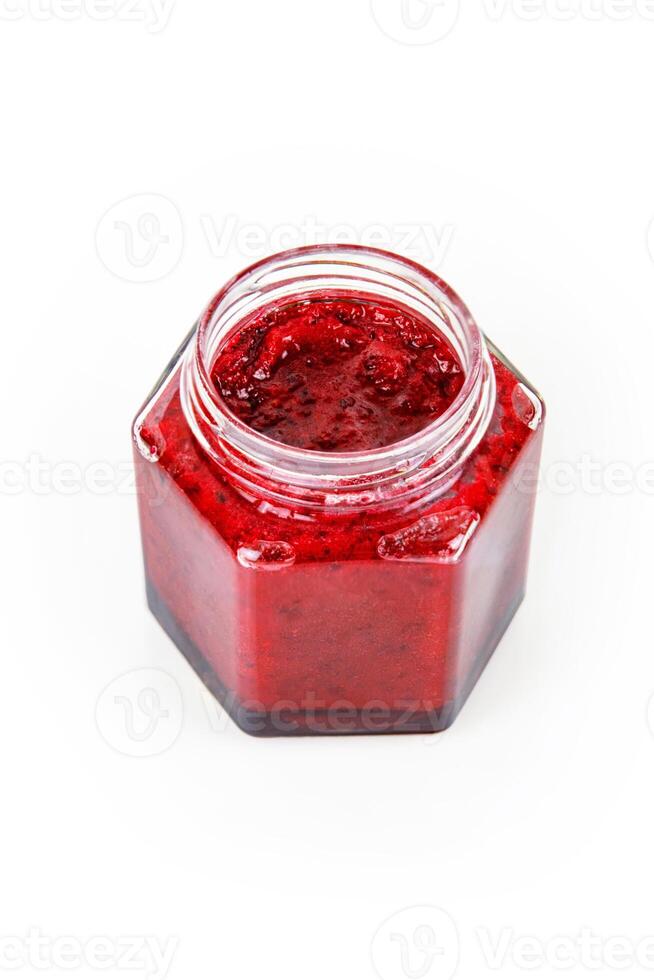Top view of fresh, vibrant red currant berry jam in an open glass jar, perfect for breakfast spreads or desserts. Closeup. Copy space. Isolated on white background. photo