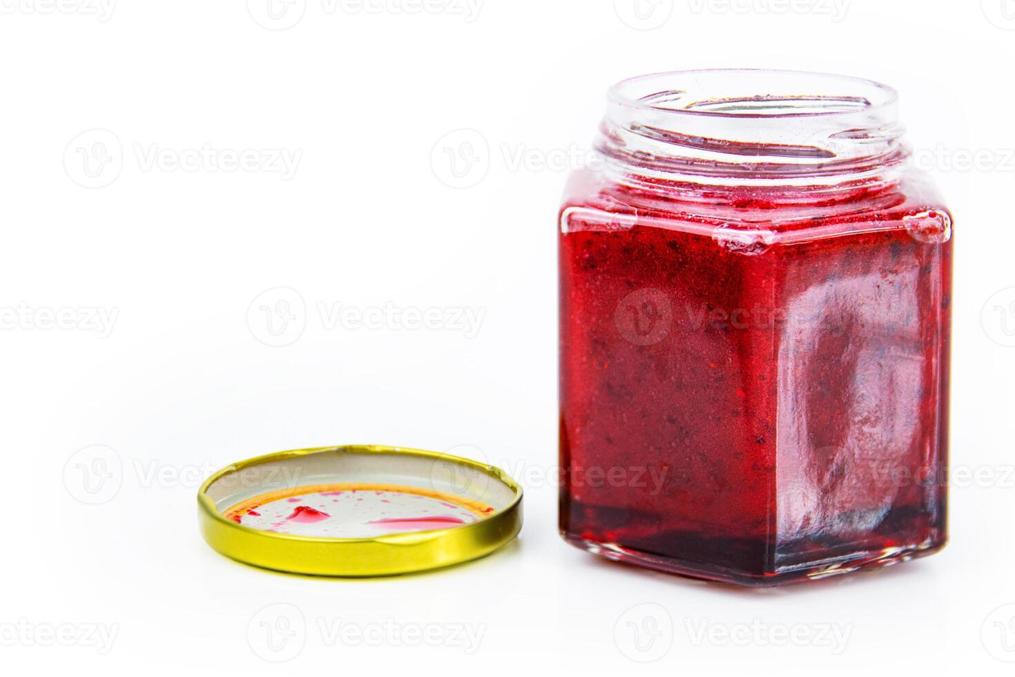 An open hexagonal glass jar of homemade red currant berry or cranberry jam with a gold lid beside it. Freshly made wild berries jelly. Copy space. Isolated on white background. photo