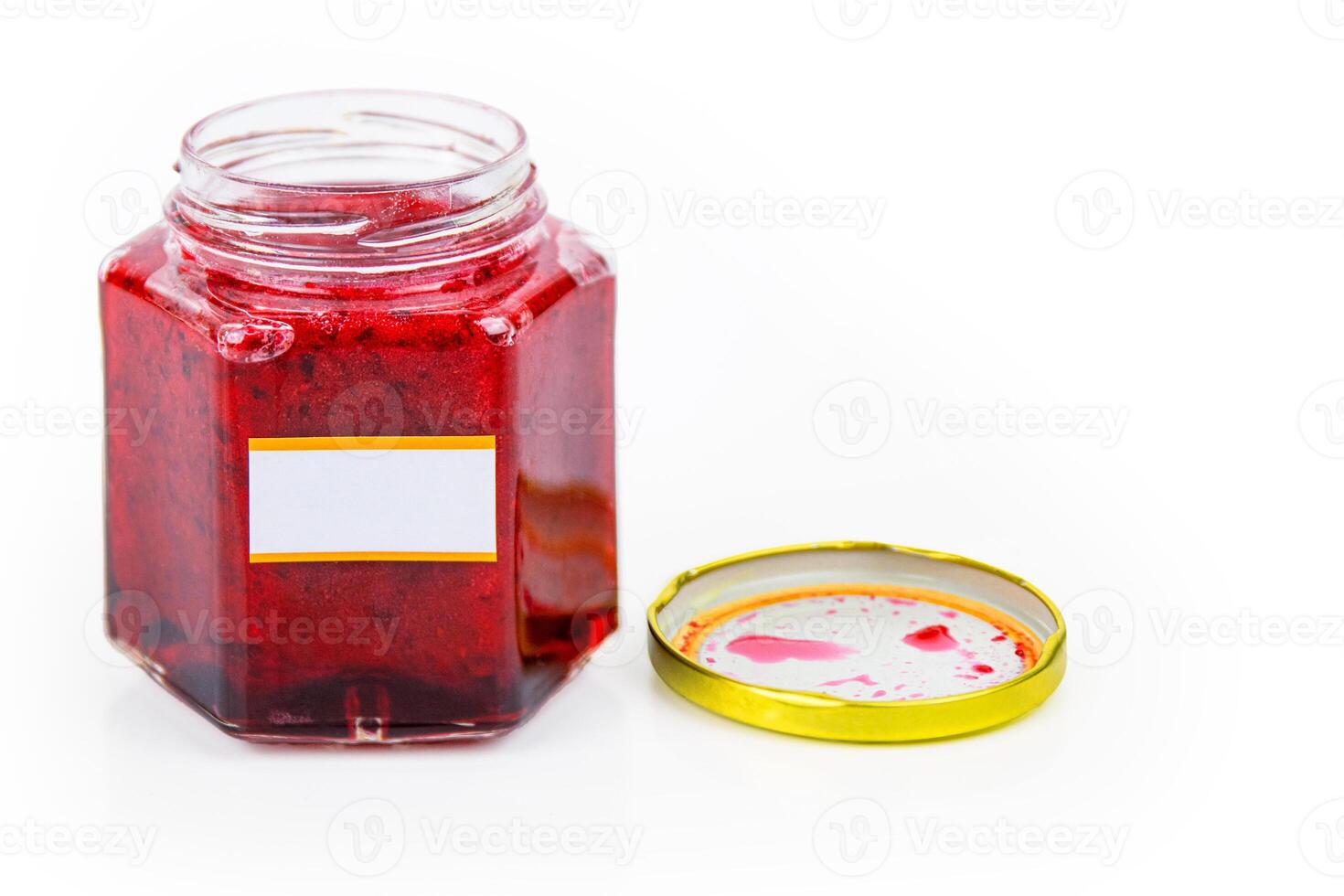 An open hexagonal glass jar of homemade red currant berry or cranberry jam with a gold lid beside it. White blank label for custom text. Copy space. Isolated on white background photo