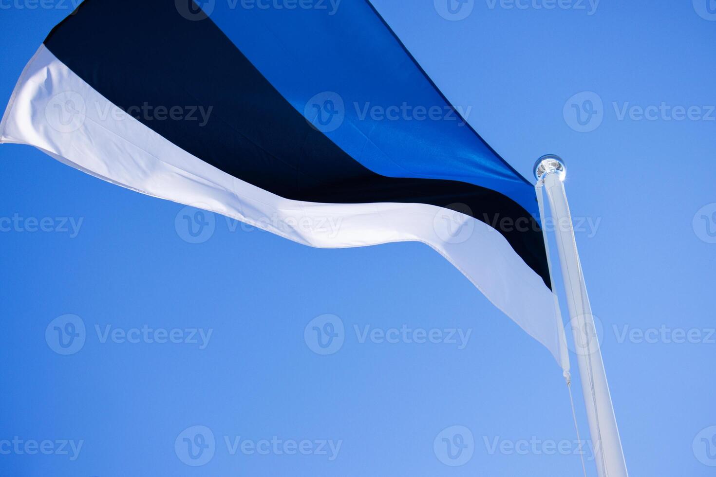 National Estonian flag waving against a clear blue sky, symbolizing national pride and identity with distinct horizontal blue, black, and white stripes. Copy space photo