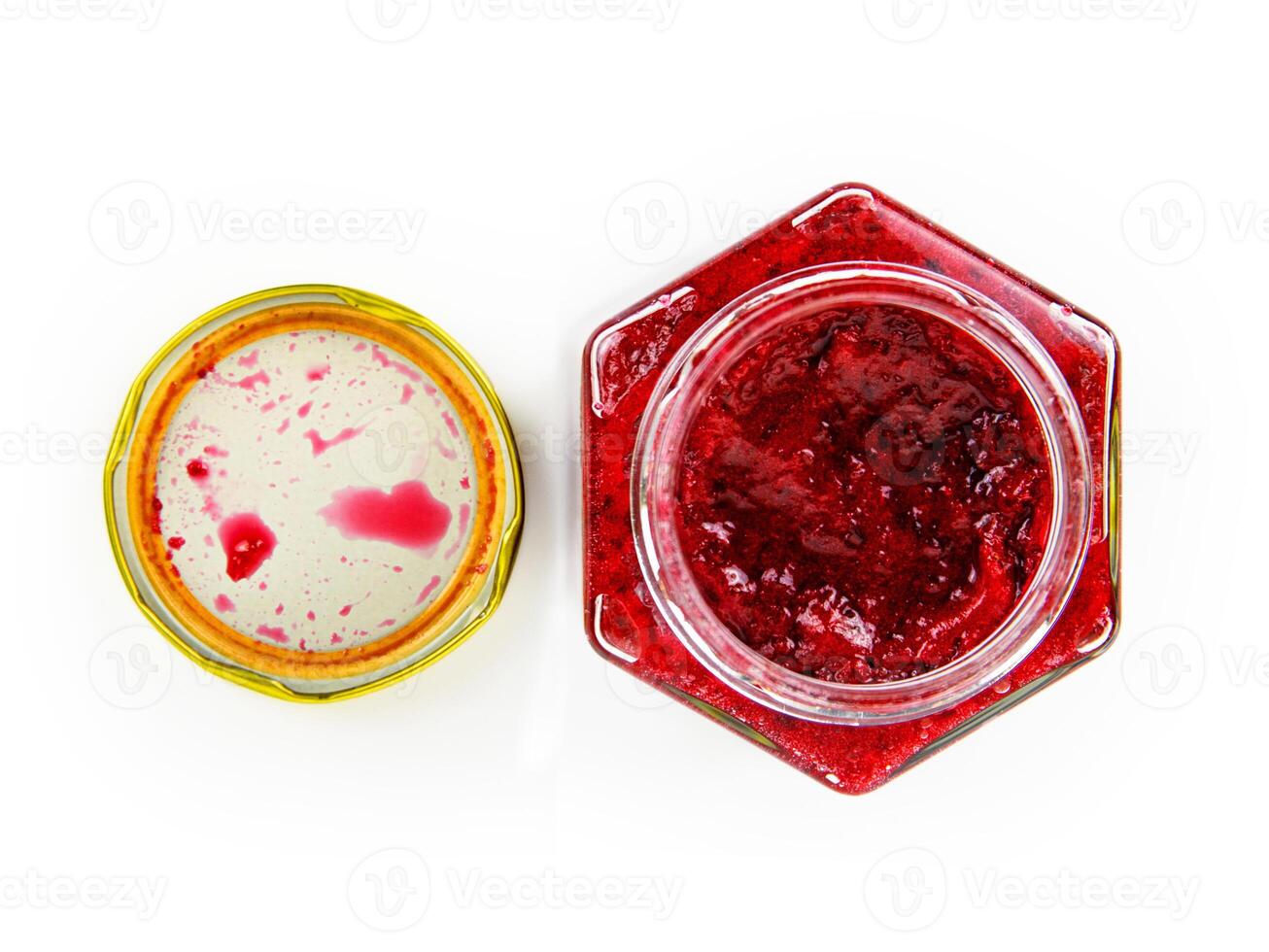 An open hexagonal glass jar of homemade red currant berry or cranberry jam with a gold lid beside it. Freshly made wild berries jelly. Copy space. Isolated on white background. Top view photo
