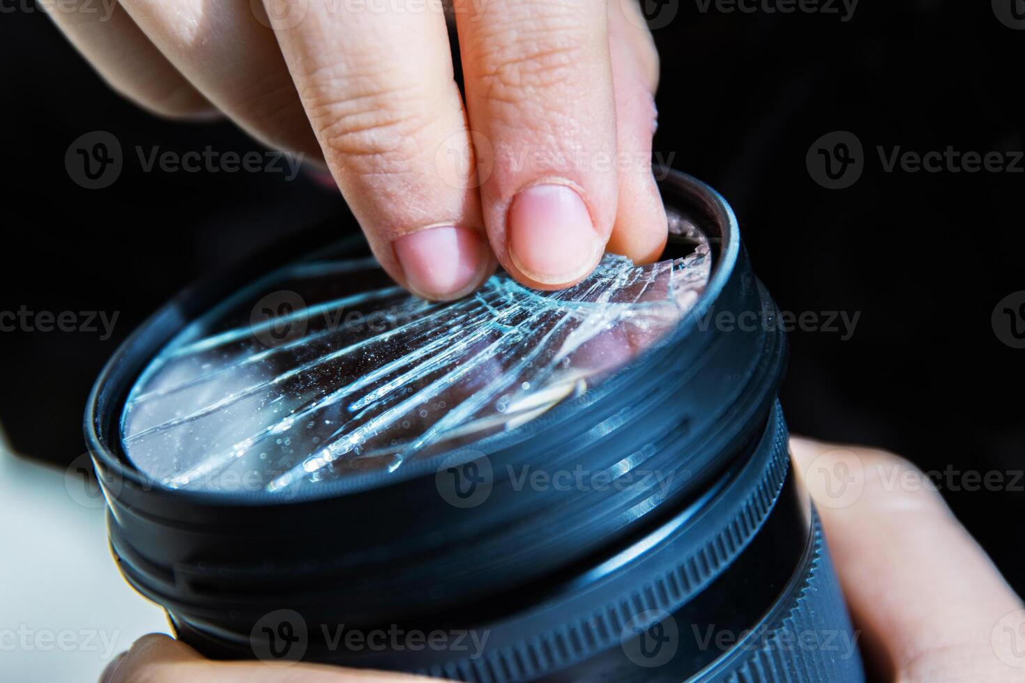 Closeup of a hand holding a broken shattered camera lens with visible cracks, symbolizing damage and fragility of photography equipment, repair or replacement needs, accidents, or fragility. photo
