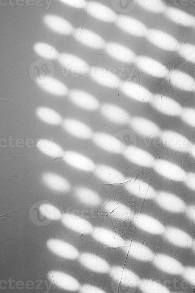 Blurred light spots, shadows from the blinds on the concrete wall on a sunny day, Natural shadow pattern on a textured white wall, formed by filtered sunlight. Copy space photo