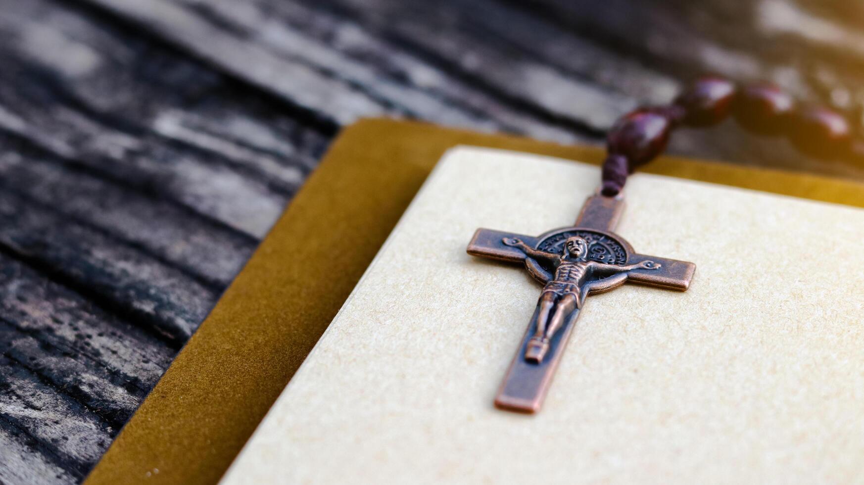 Shiny copper cross leaning against an old open book symbolizing the spread of Jesus Christs love among Christians reflecting faith devotion and the importance of Christian teachings. photo