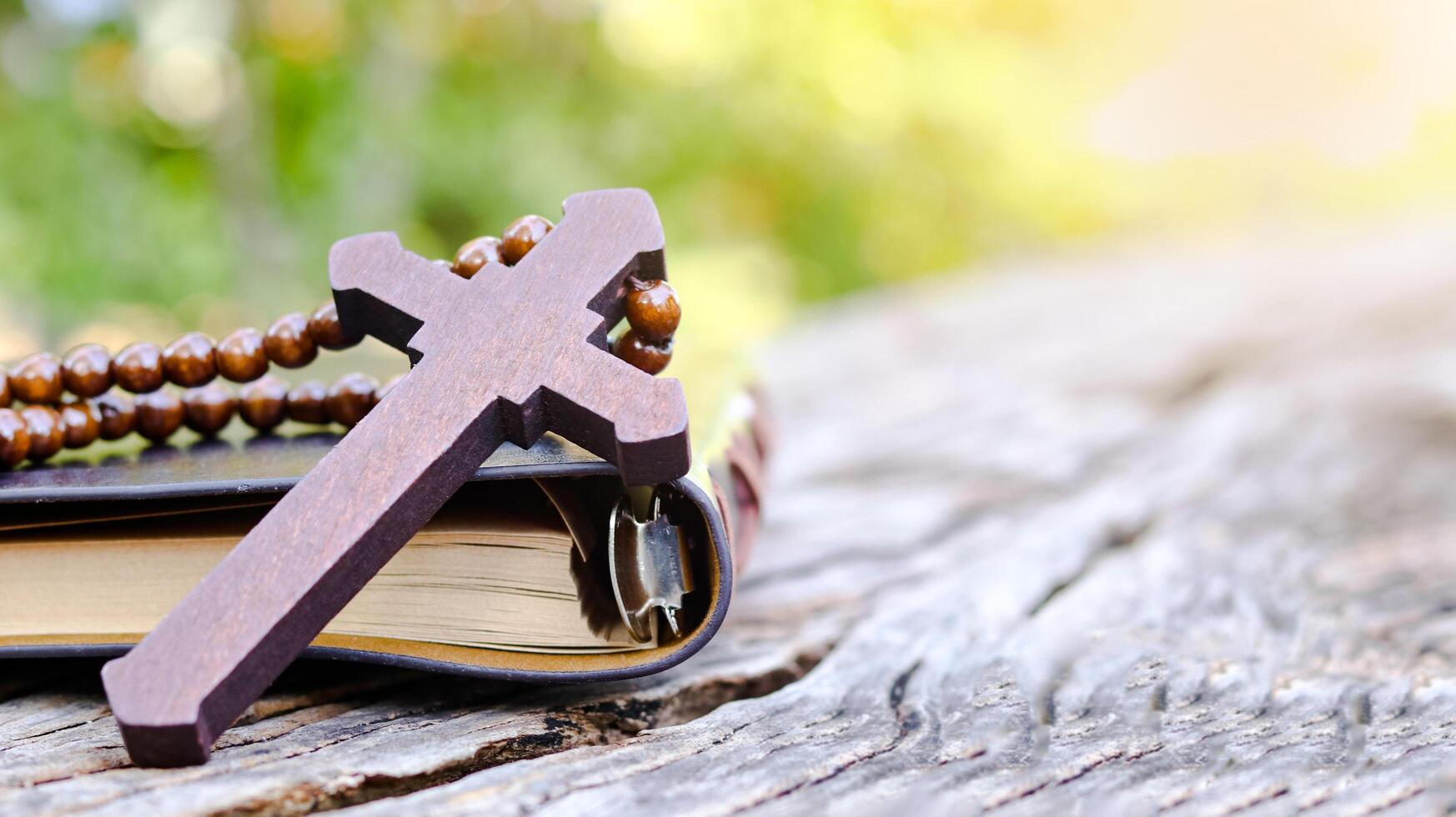 Dark red wooden cross leaning against an old open book symbolizing the spread of Jesus Christs love among Christians reflecting faith devotion and the importance of Christian teachings. photo