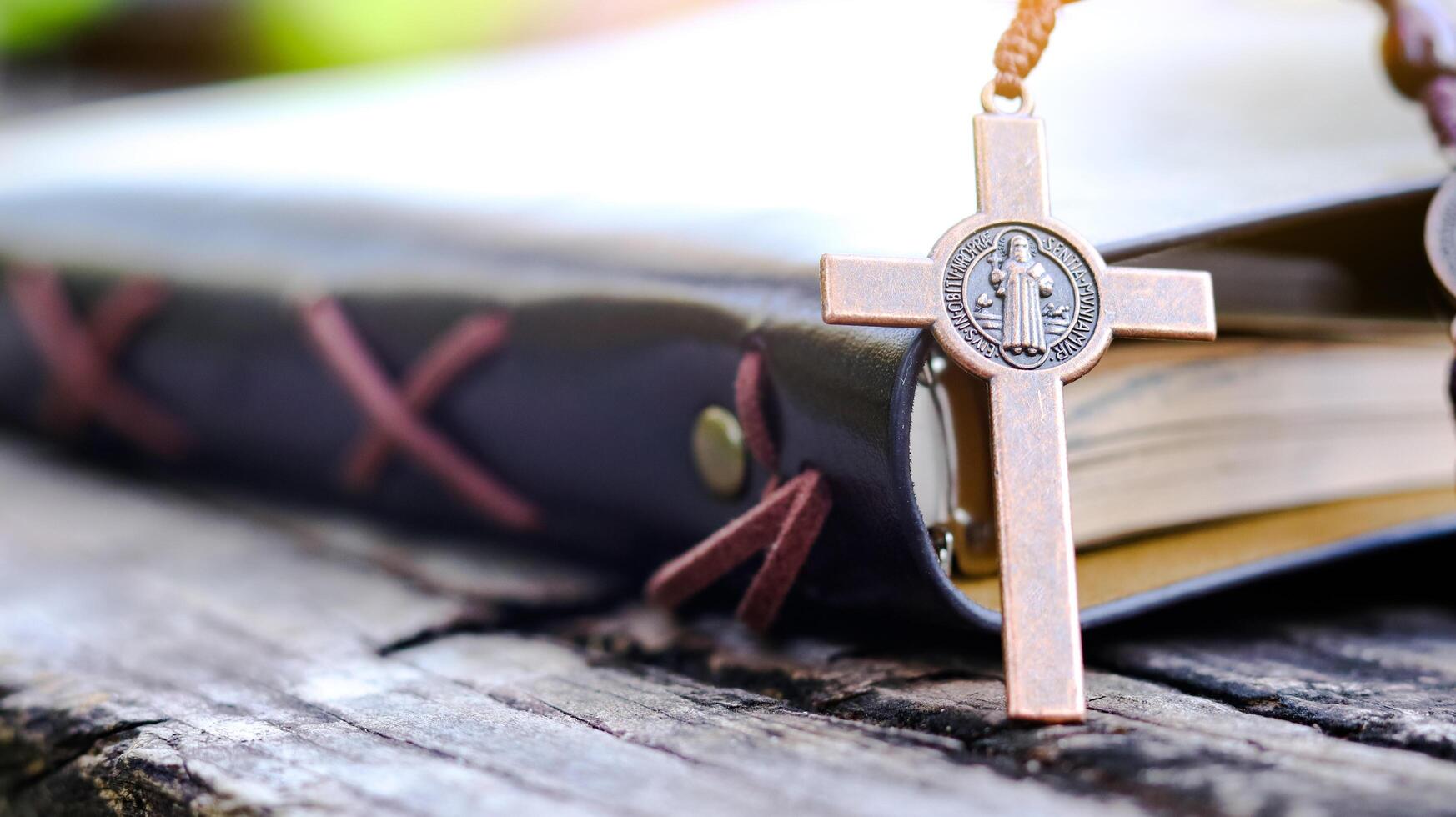 Shiny copper cross leaning against an old open book symbolizing the spread of Jesus Christs love among Christians reflecting faith devotion and the importance of Christian teachings. photo