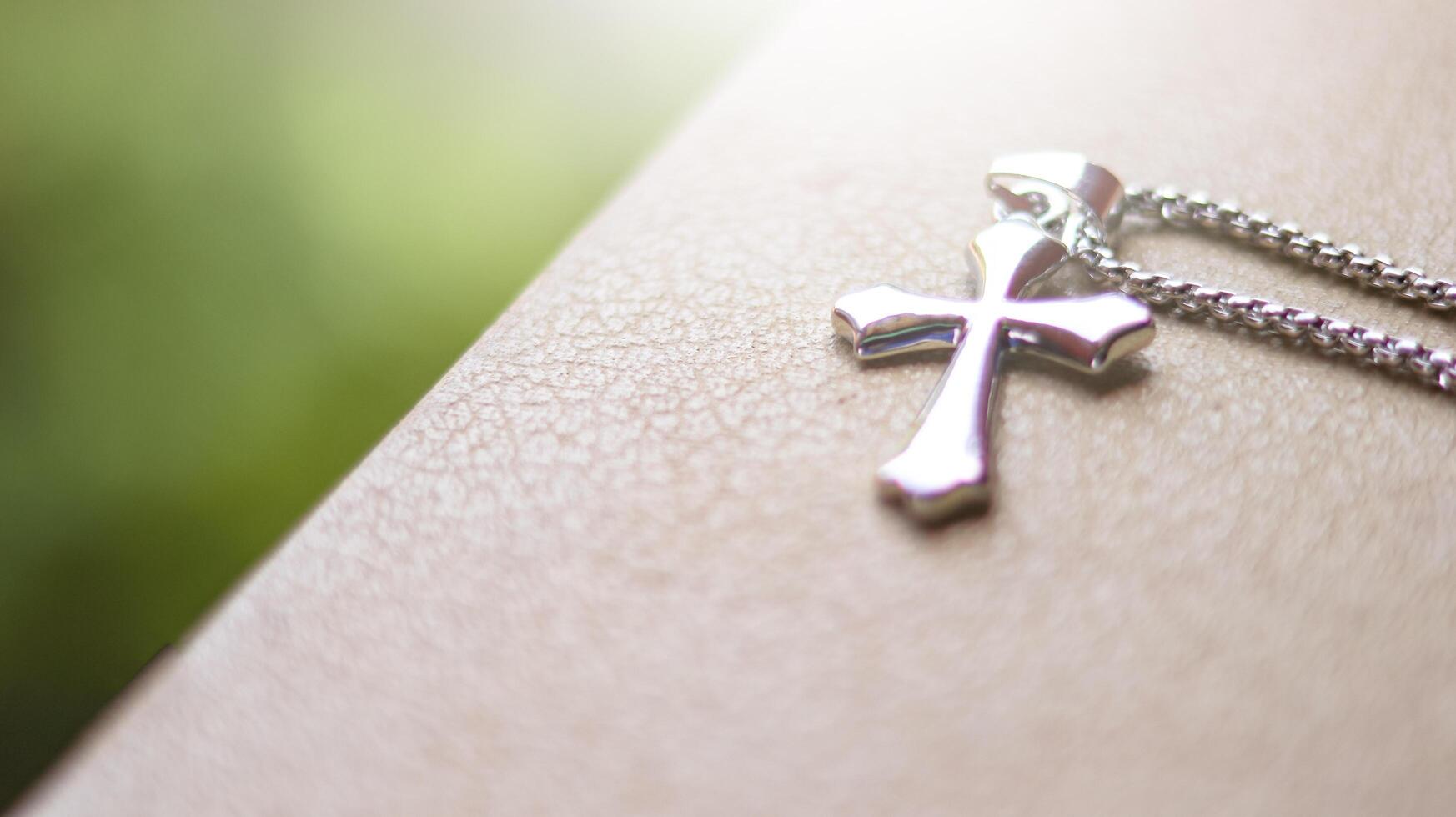 Shiny metal cross leaning against an old open book symbolizing the spread of Jesus Christs love among Christians reflecting faith devotion and the importance of Christian teachings. photo
