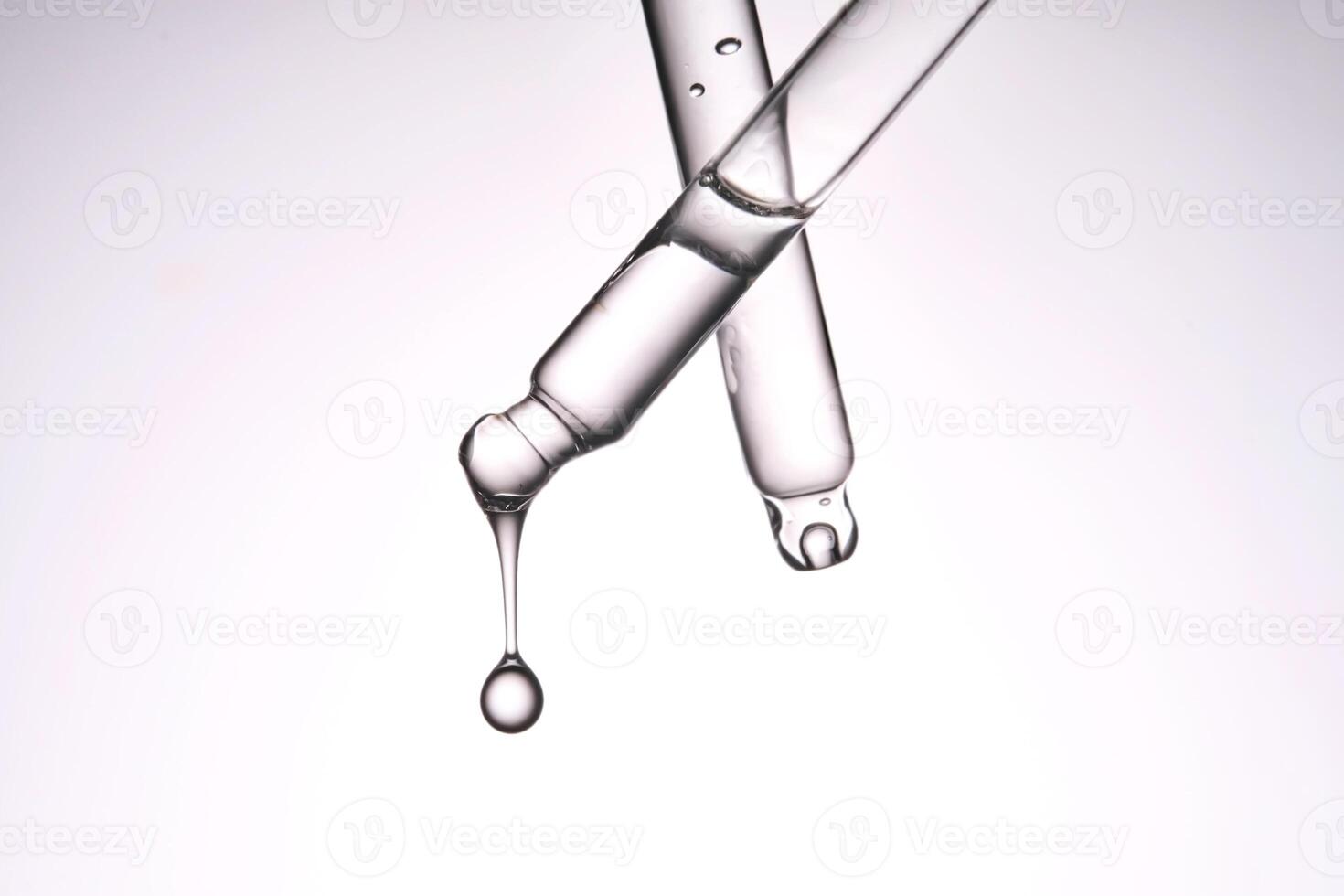 Two pipettes with a cosmetic product. Serum or fluid drips from one of them. photo