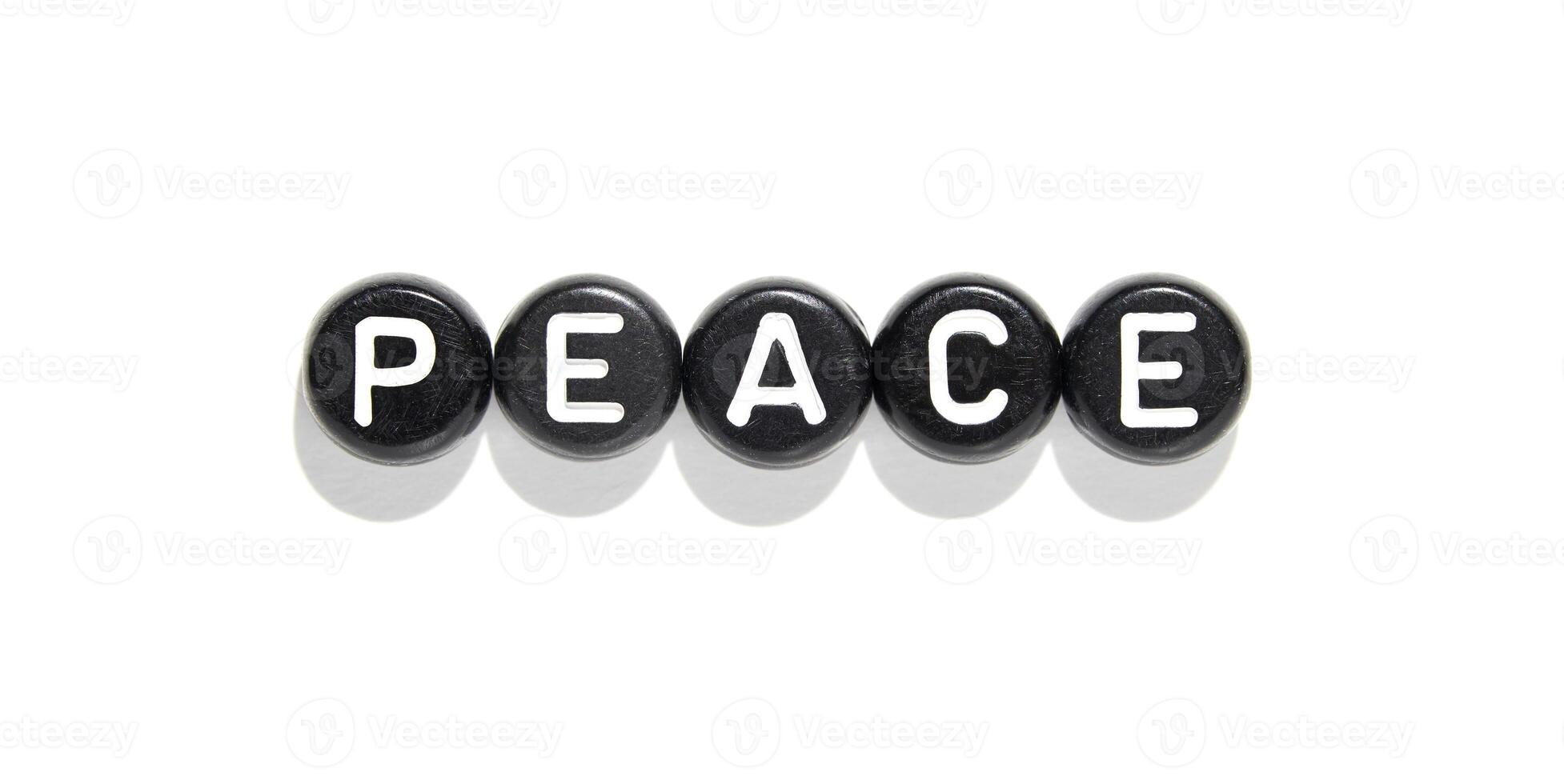 Black round beads with white letters spelling peace on white background for mindfulness and harmony concepts. photo