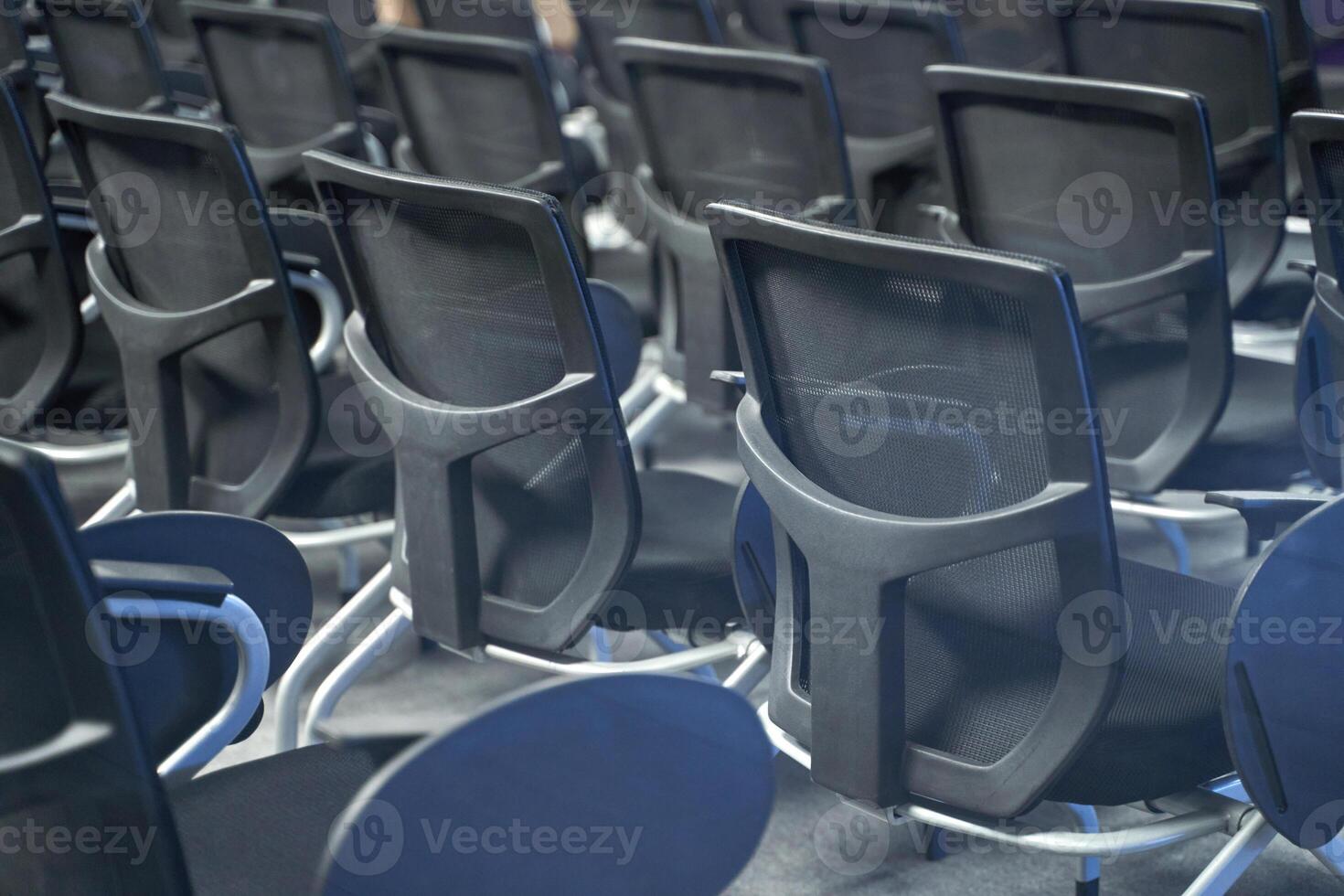 Empty conference room with rows of modern black office chairs arranged in neat alignment at corporate meeting venue photo
