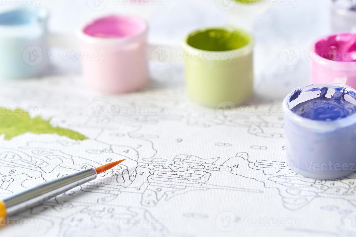 Paint by numbers relaxation art with colorful paint jars and brush on unfinished canvas. photo