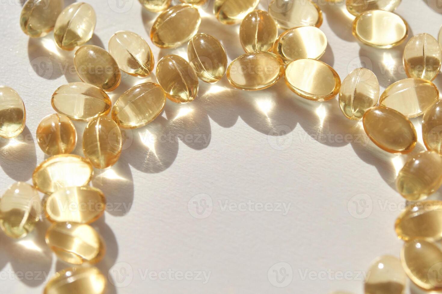 Shiny transparent capsules arranged in circle on white surface with sunlight reflection photo