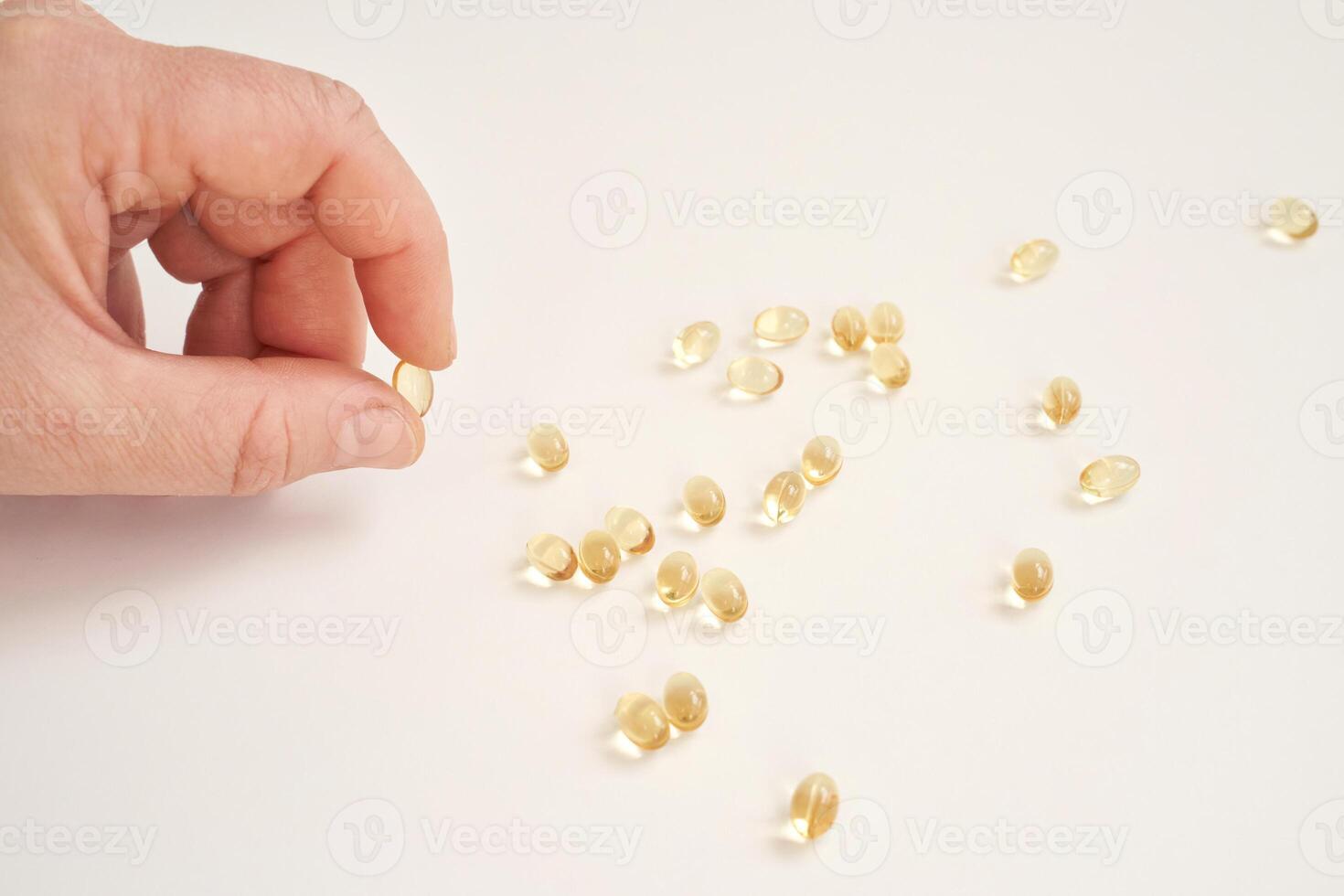 Hand picking up fish oil capsules on white background. health and wellness concept featuring omega-3 supplements photo