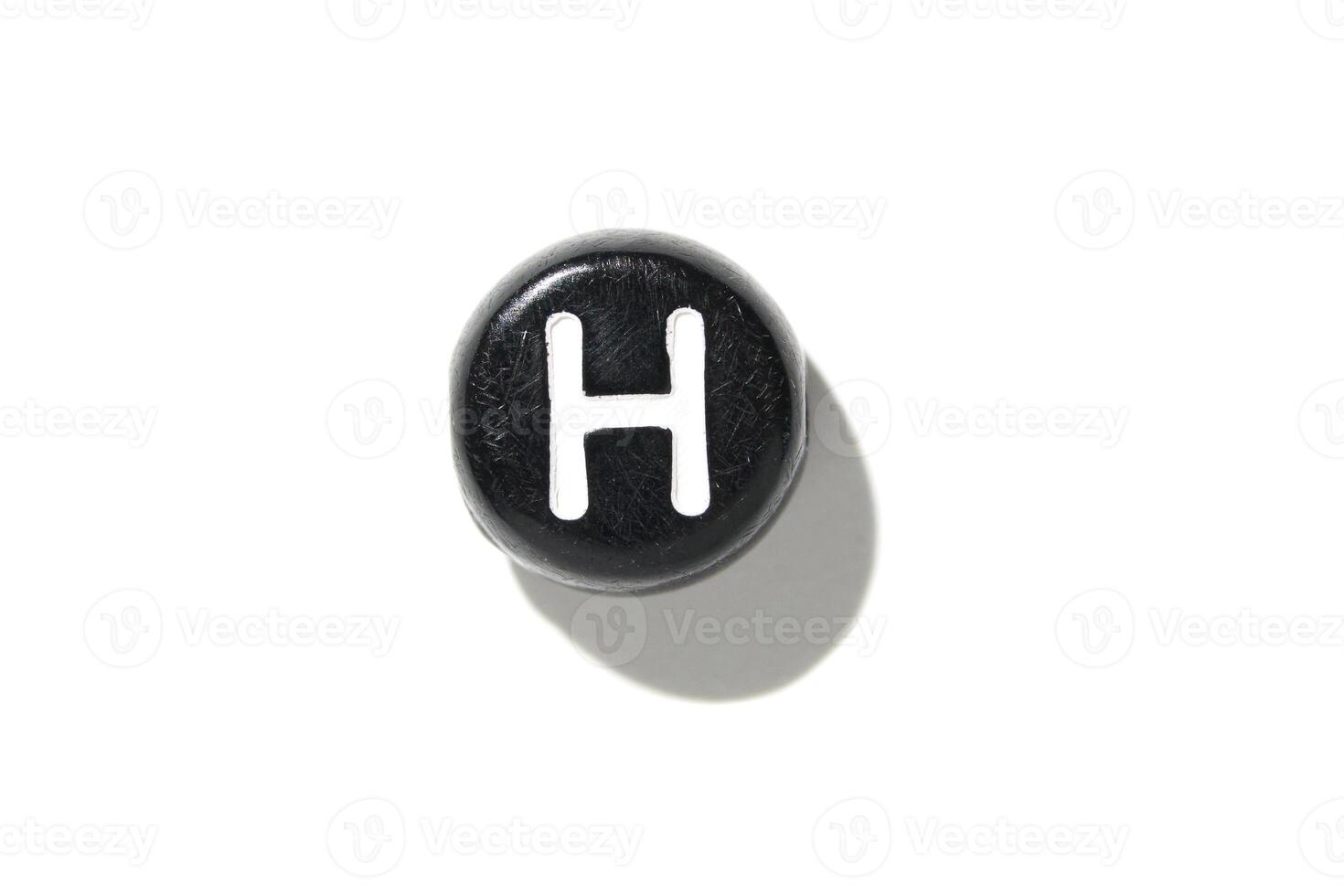 Black round chess piece with white h on white background represents education and strategy concepts photo