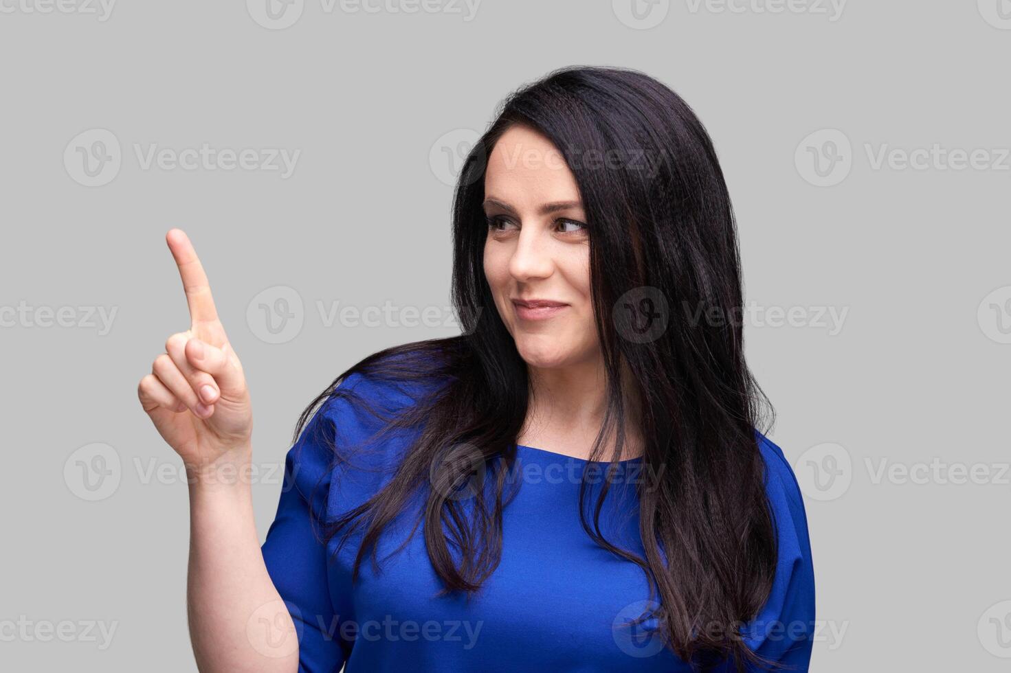 Confident woman gesturing with finger in blue top on gray background. photo