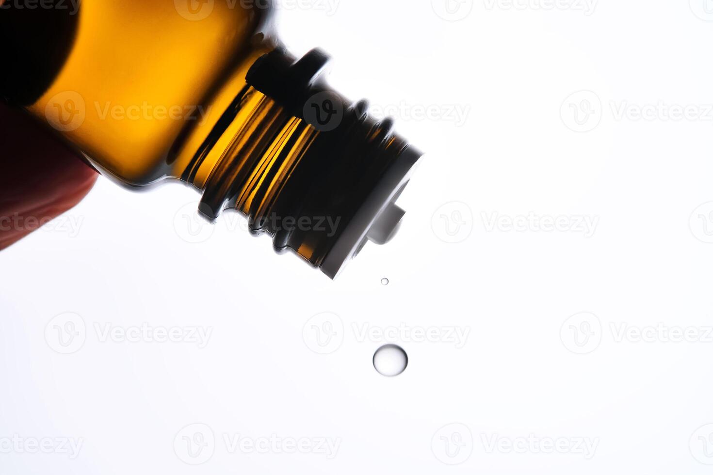 A drop of antihistamine or essential oil drips from a bottle. Close-up. photo